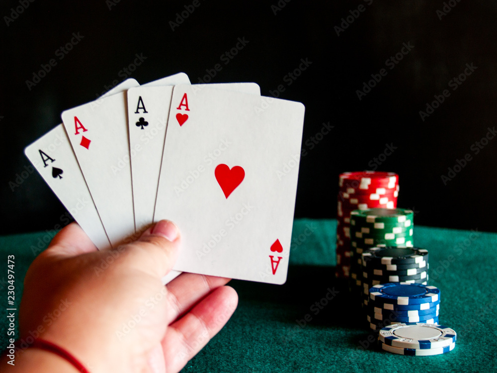 Obraz premium A person playing poker with the four aces of a deck in his hand and poker chips of various colors on a green mat