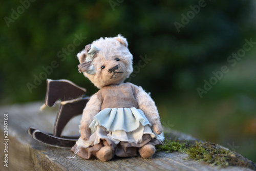 Toy teddy Bear sits on a green background.