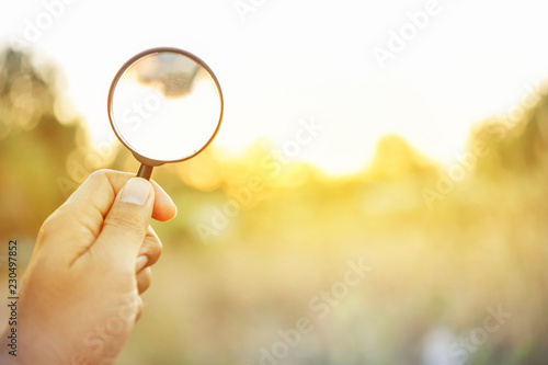 Hand hold magnifying glass on orange light ray