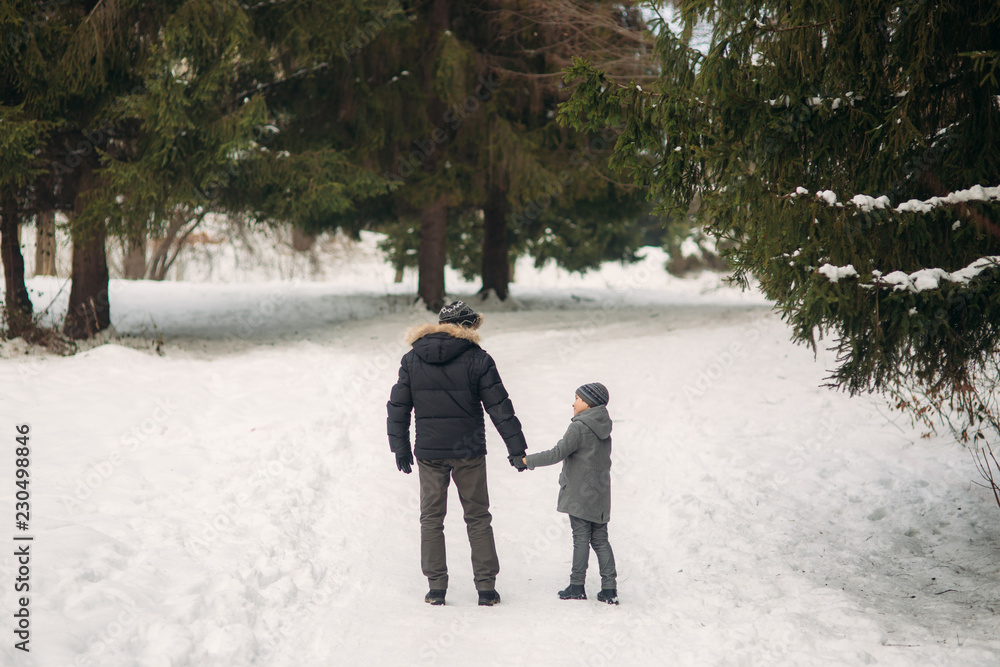 Happy father with his son walks through the park in the snowy winter weather Happy father with his son walks through the park in the snowy winter weather