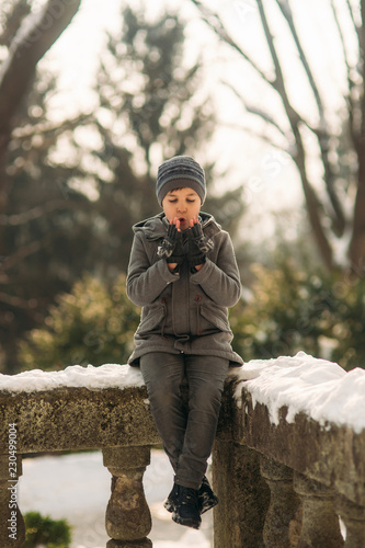 Little boy warming his hands. Winter weather. Snow around