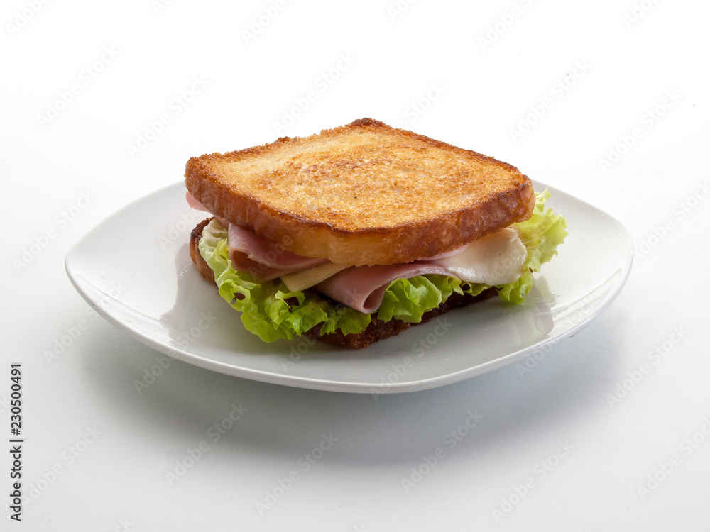 Sandwich de jamón y queso con lechuga dentro de un plato ovalado blanco, sobre fondo blanco 2 Sandwich de jamón y queso con lechuga dentro de un plato ovalado blanco, sobre fondo blanco 2