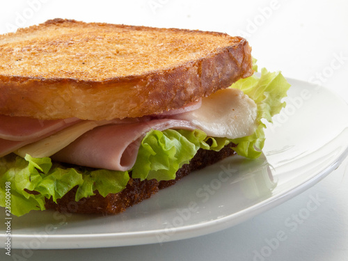 Sandwich de jamón York y queso  con lechuga dentro de un plato , sobre fondo blanco
