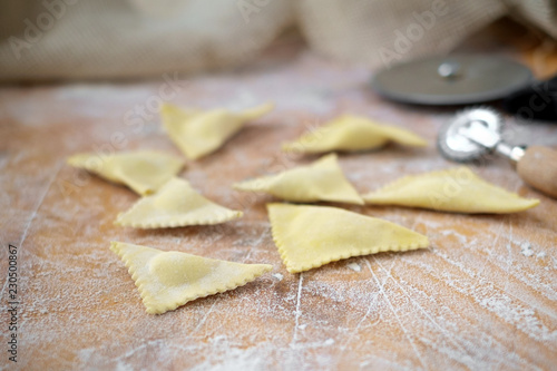 raw triangular ravioli on a wooden kitchen table in flour, cooking homemade pasta