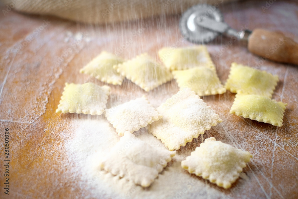 Raw natural ravioli sprinkle with flour on a wooden table at the time of manufacture