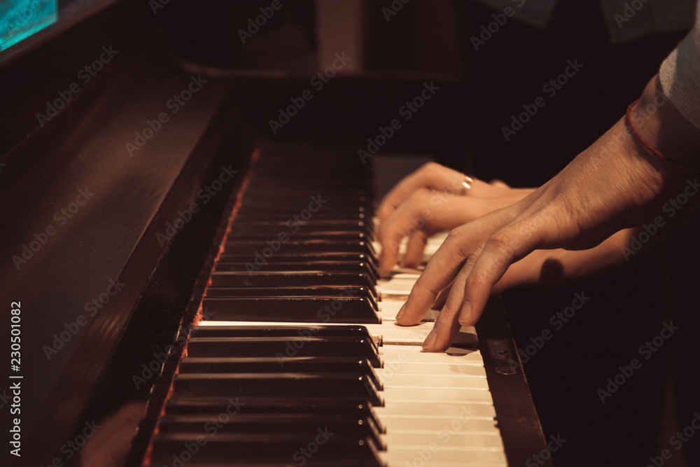 women's hands on the piano keys, playing a melody