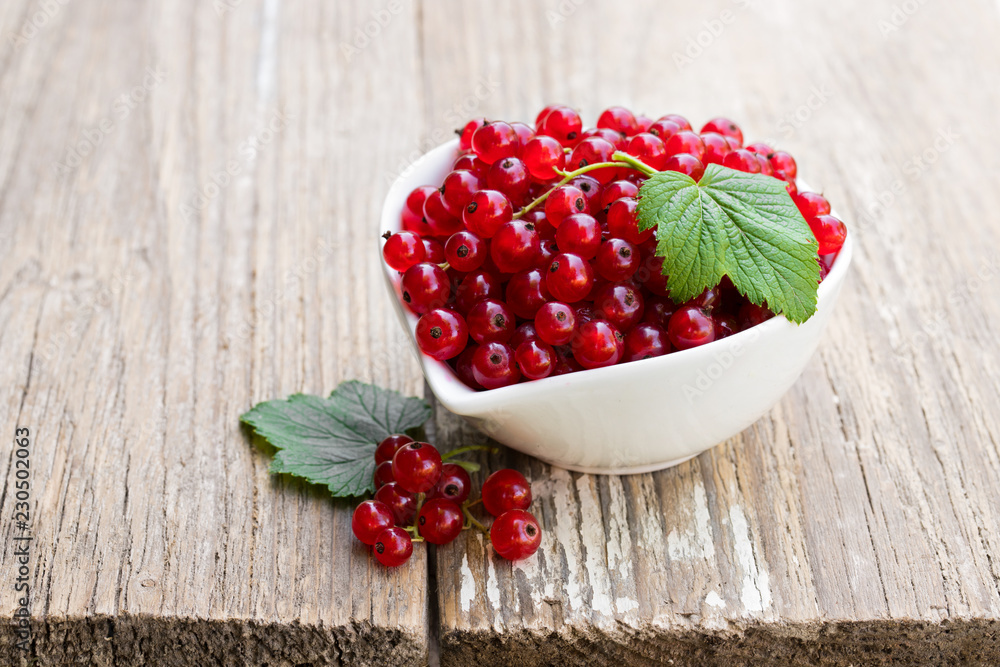 Fresh red currant in ceramic bowl on wooden table Fresh red currant in ceramic bowl on wooden table