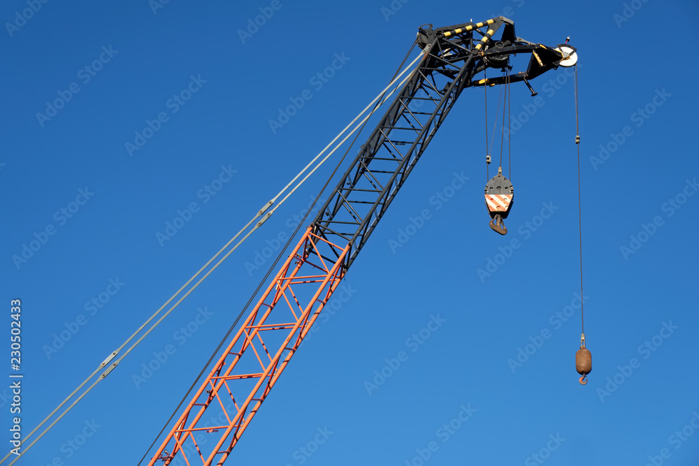 Tower crane high in blue sky close up of lifting hook