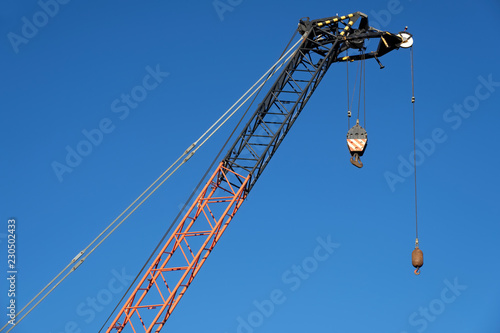 Tower crane high in blue sky close up of lifting hook