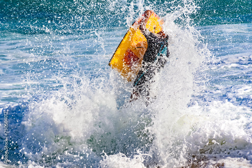 Flight of bodyboarder boy when crashing wave on the beach