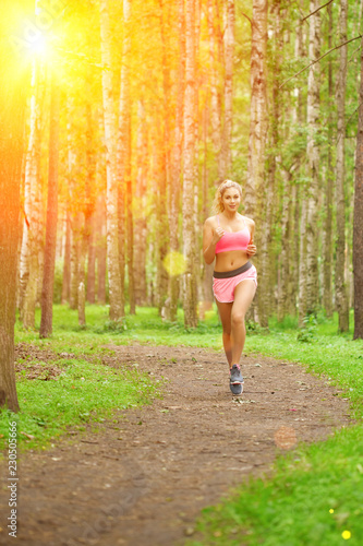 Young woman sports, running in the park. Girl model runs at sunrise or sunset outdoors. Healthy lifestyle, jogging.