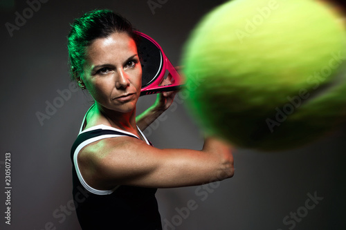 Adult fitness woman playing padel indoor. Isolated on black.