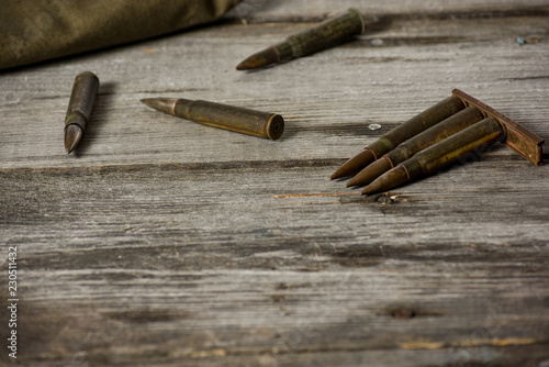 Disassembled clip with cartridges 7,92 x 57 - rustic ammos and poncho lies on the wooden background