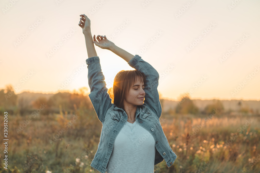 Fototapeta premium Autumn Girl enjoying nature on the field. Beauty Girl Outdoors raising hands in sunlight rays. Beautiful Teenage Model girl