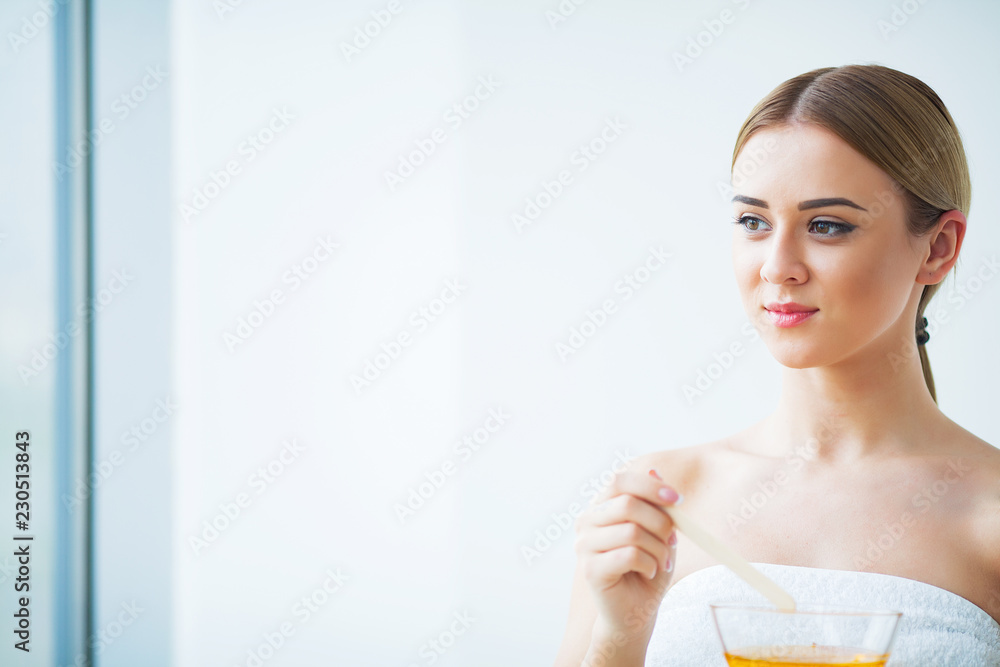 Women hold orange paraffin wax bowl. Woman in beauty salon Women hold orange paraffin wax bowl. Woman in beauty salon