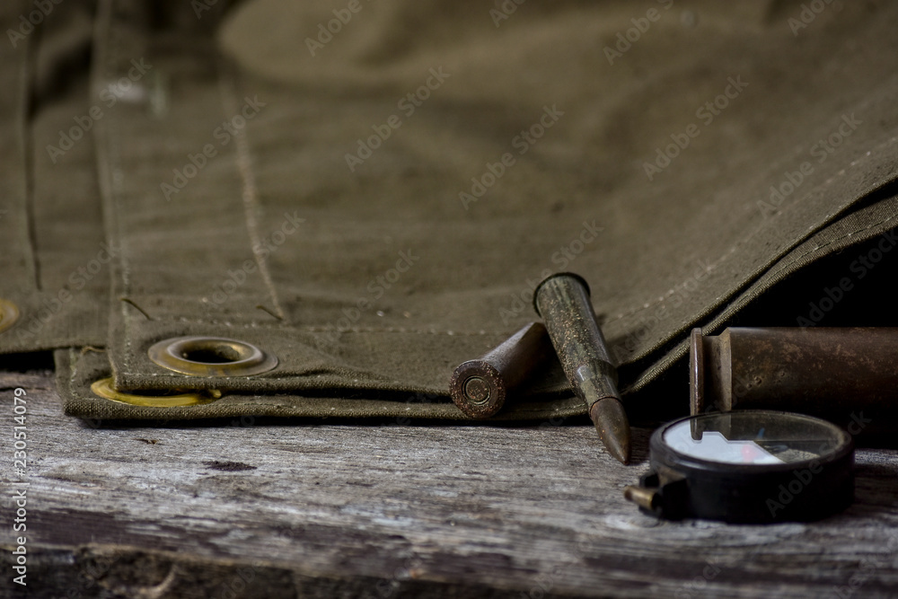 7,92 x 57 - rustic ammos, poncho and old compas lies on the wooden background 7,92 x 57 - rustic ammos, poncho and old compas lies on the wooden background