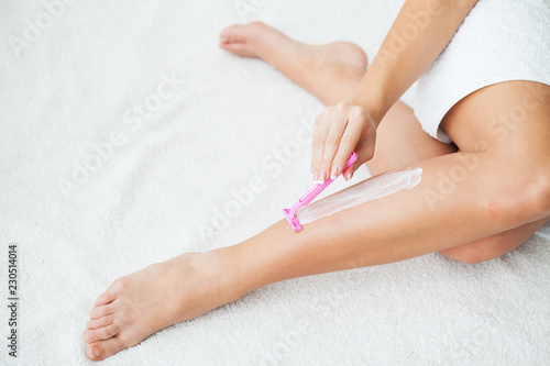Caucasian woman shaving legs with razor at home