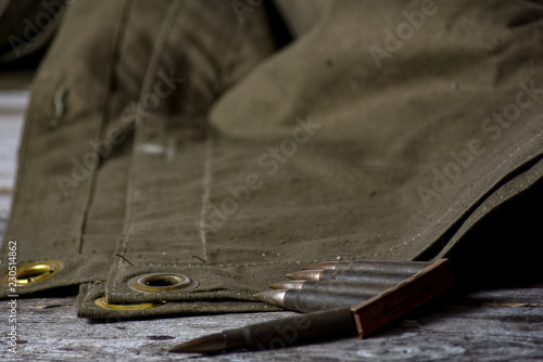 Holder with cartridges 7 92 x 57 - rustic ammos and poncho lies on the wooden background