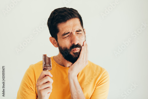 Man have sensitive teeth with ice on white background