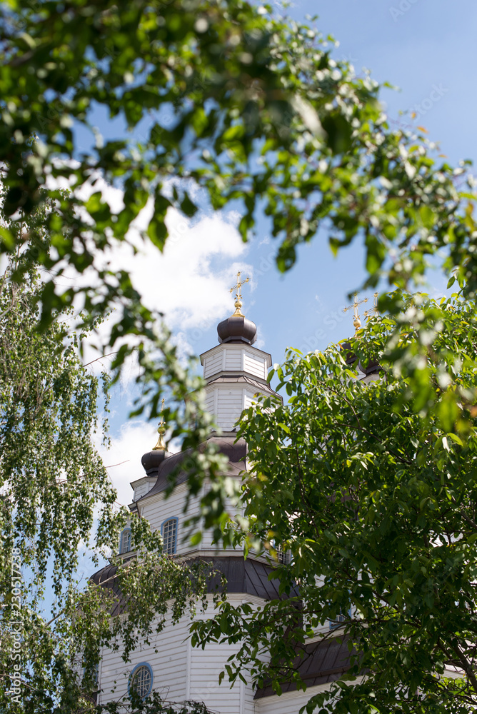 The modern architecture of Catholic Church with big green trees and beautiful cloudy sky The modern architecture of Catholic Church with big green trees and beautiful cloudy sky