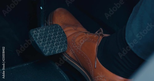 CU business man in brown leather shoes pressing the acceleration pedal in a modern car. 4K UHD photo