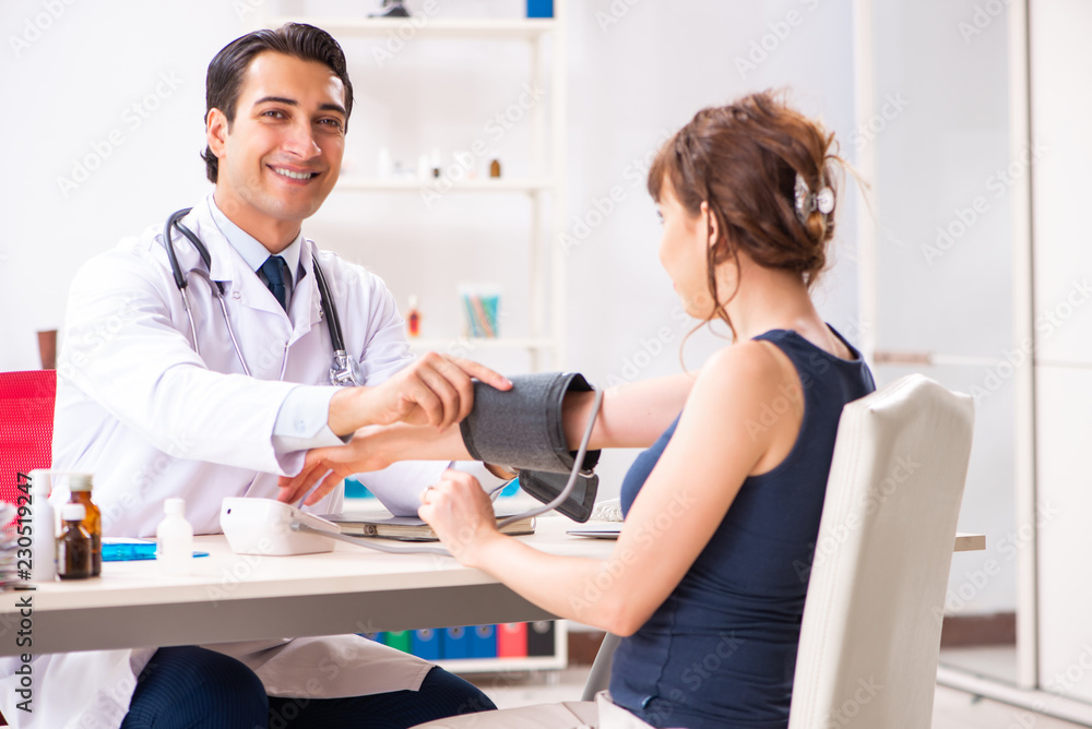 Fototapeta premium Young doctor checking woman's blood pressure