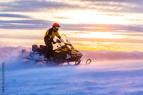 A man is ridind snowmobile in mountains. photo