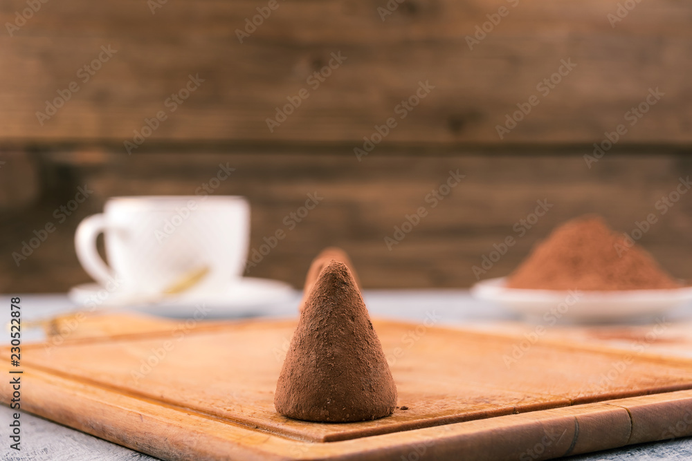 Chocolate candy in cocoa powder on wooden background. Chocolate candy in cocoa powder on wooden background.