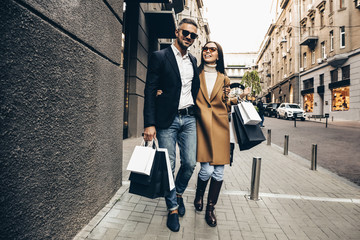 Shopping. Black Friday. Couple. Love. Man and woman with shopping bags are hugging and smiling while walking down the street