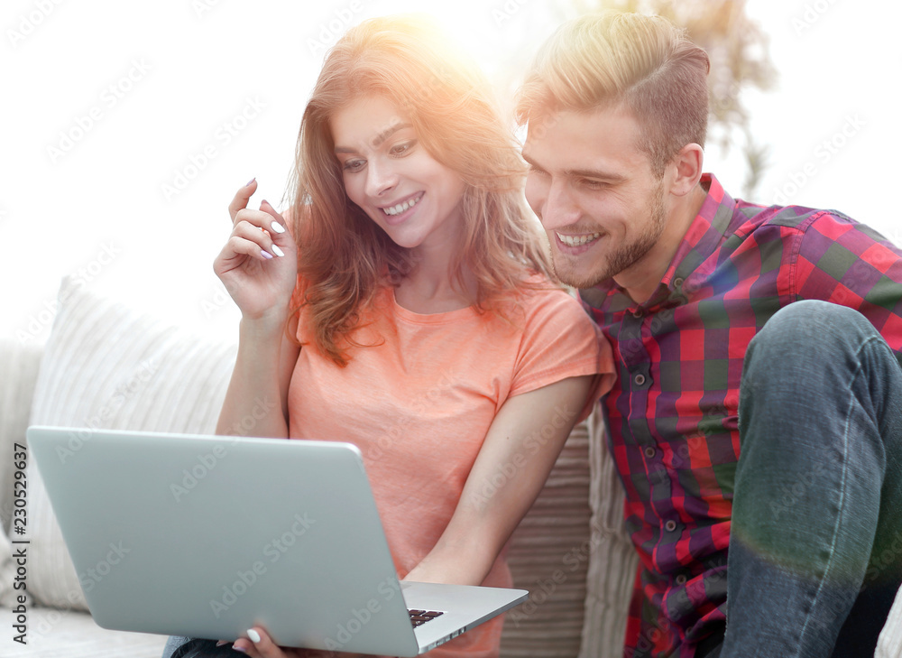 young man with his girlfriend watching a TV show on the laptop sitting in the living room young man with his girlfriend watching a TV show on the laptop sitting in the living room