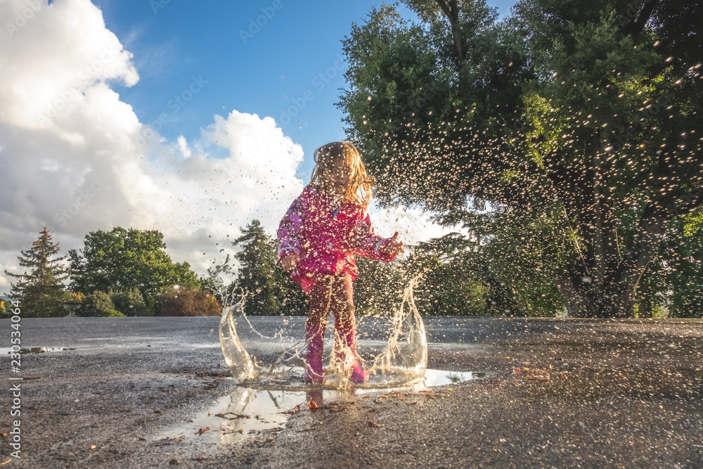 Girl jumping into the huge puddle