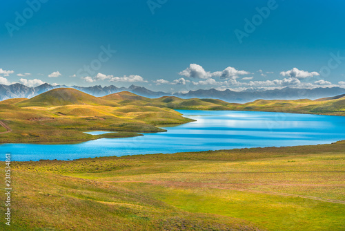 Landscape with mountain lake. Azure water. Mountain river. Top landscape of beautiful nature. Green hills. Snowy peaks. Sunny summer day.