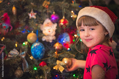 Cute happy girl decorating Christmas tree