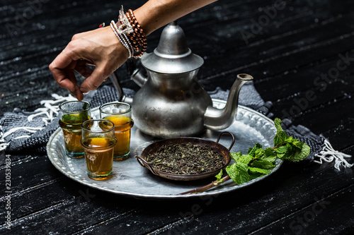 Woman putting mint leaves into tea