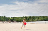 caucasian shirtless man holding red beach ball on sandy beach