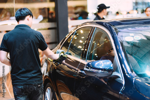 SAIGON EXHIBITION AND CONVENTION CENTER (SECC), HO CHI MINH CITY, VIETNAM - OCTOBER 2018: Unidentified man car cleaner. A man cleaning car with microfiber cloth, car detailing (or valeting) concept photo