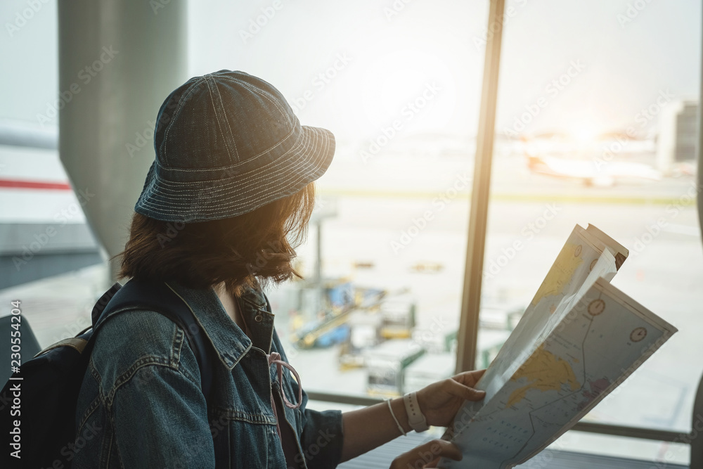 Young woman hold map planning vacation trip at airport. Travel concept.