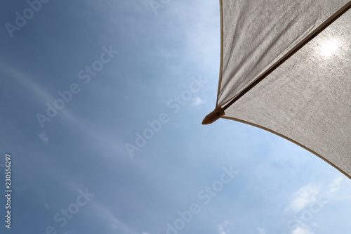 Closeup of a part of white handmade cotton umbrella  with bright blue sky background.