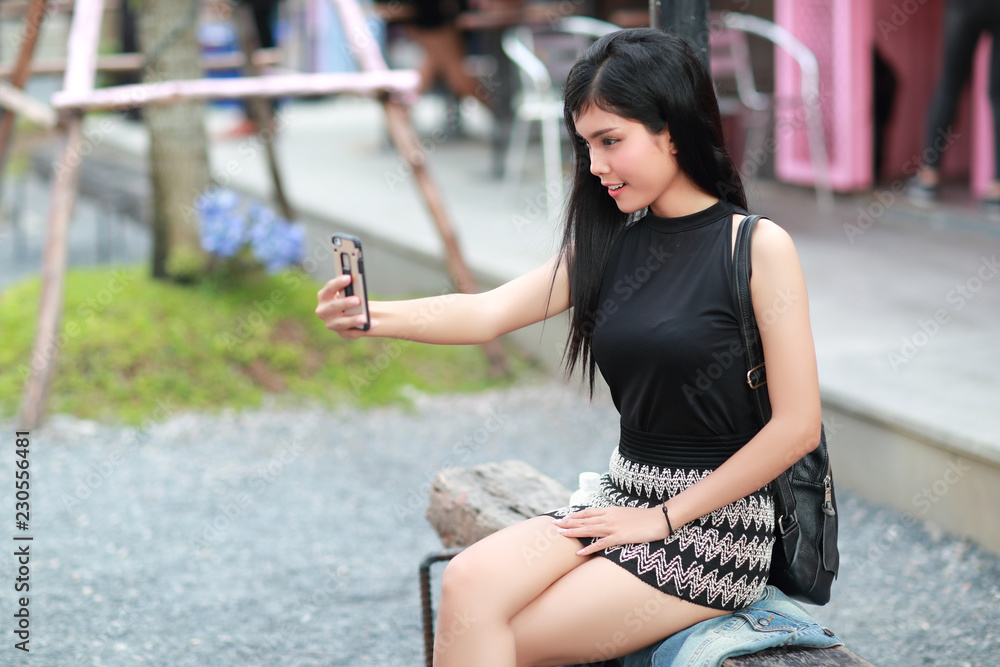 Fototapeta premium Young asian traveler using smart phone and do self portrait while traveling during holiday vacation