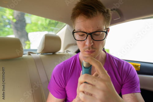 Face of man using asthma inhaler in back seat of car © Ranta Images