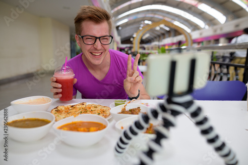 Young man vlogging with mobile phone in Indian restaurant © Ranta Images
