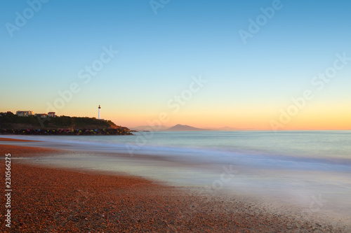 Plage des sables d'or au coucher du soleil en pose longue avec vue sur le phare de biarritz photo