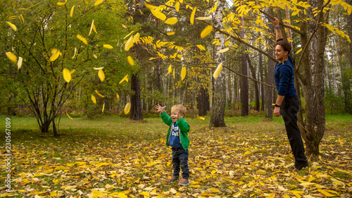A 5 year old child rejoices at the yellow leaves falling from a tree.