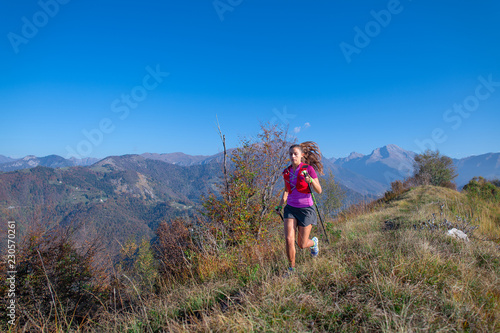 Young woman runs with poles in the mountains