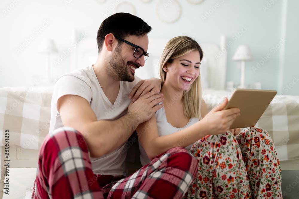 Young attractive couple using tablet in bedroom Young attractive couple using tablet in bedroom