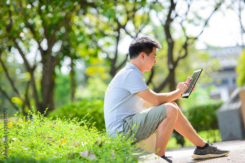 Young asian man using tablet in park