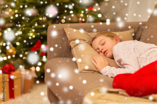 christmas, holidays and childhood concept - girl sleeping on sofa at home © Syda Productions