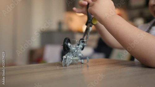 Baby boy plays with meccano bike and needle-nose pliers. Close up of hand tools photo