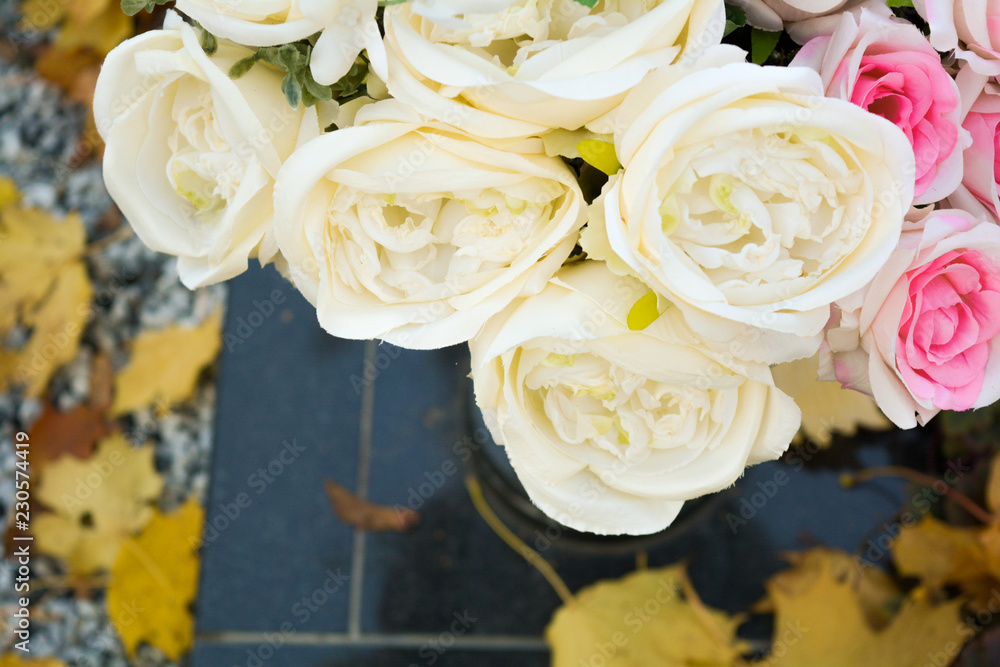 Bouquet of pink and white rose flowers, autumn fallen leaves on ground Bouquet of pink and white rose flowers, autumn fallen leaves on ground