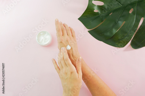 Female hands and flowers on a pink background. Skin and hand car